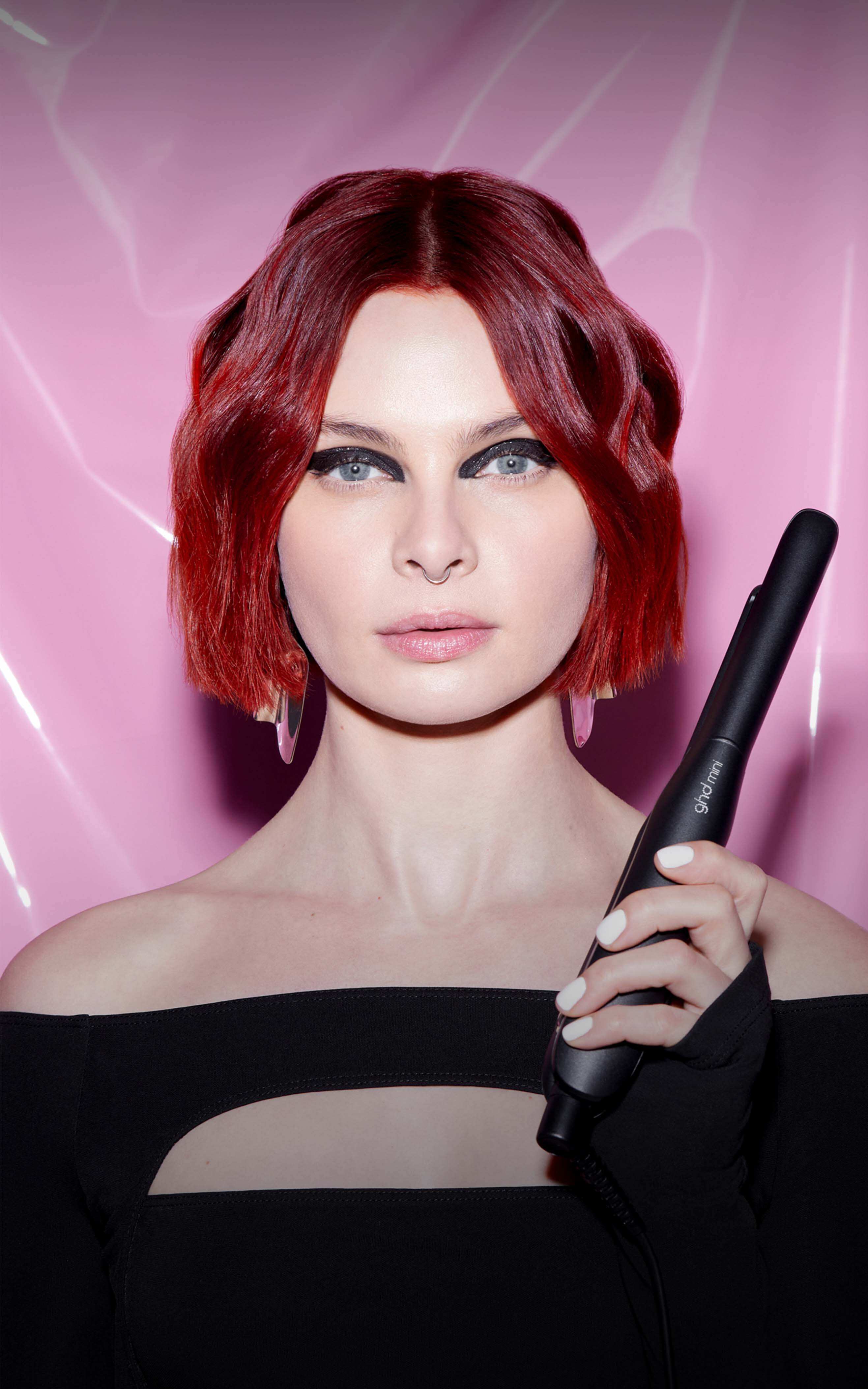Model mit kurzen roten Haaren hält den ghd mini