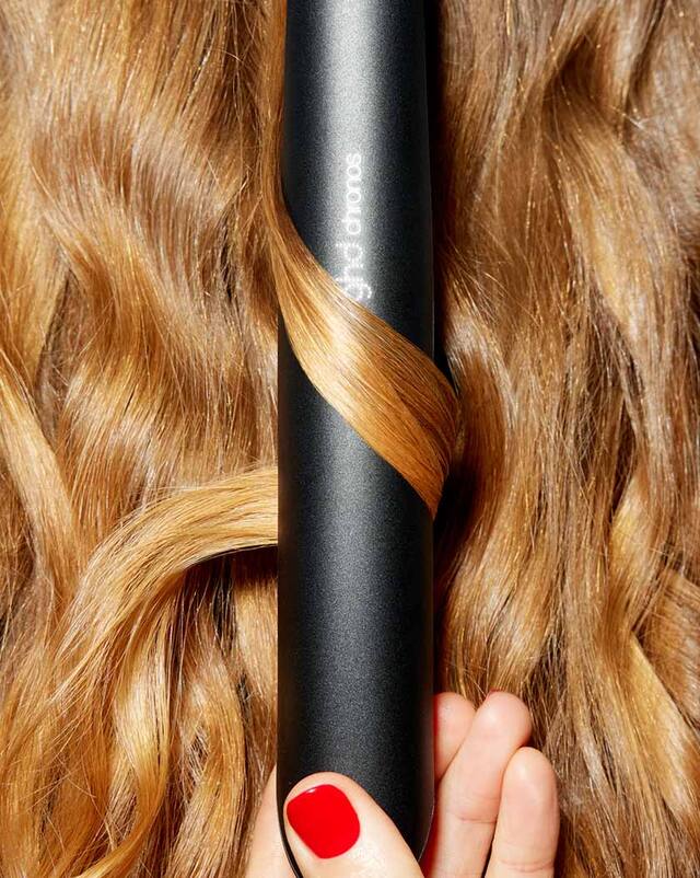 schwarzes ghd chronos Glätteisen in welligem Haar